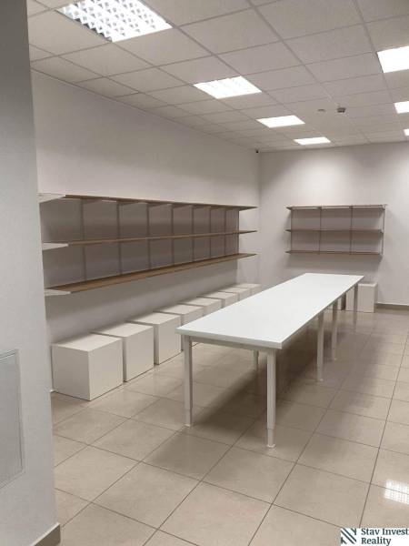 Commercial space with a long table, shelves, and white cubes on the floor.