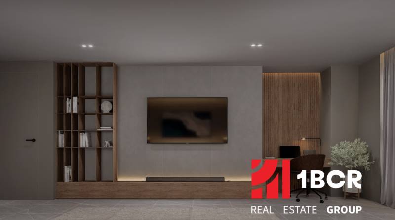 A minimalist living room in a three-room apartment with a television and bookshelves.