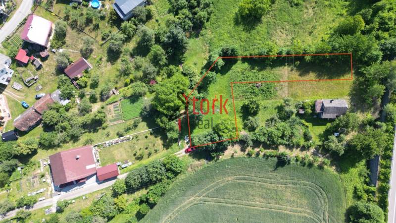 Aerial view of a residential plot in the village of Visolaje surrounded by greenery and houses.
