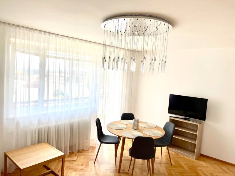 Living room in a two-room apartment with a round table, armchairs, and a television.