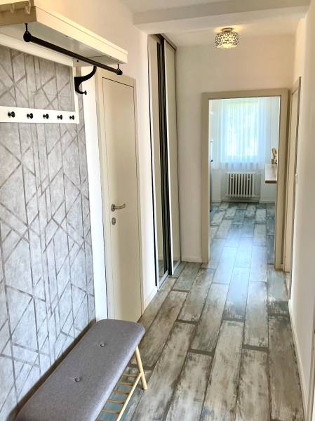 A hallway in a 2-room apartment with a bench, a coat rack, and a built-in wardrobe.