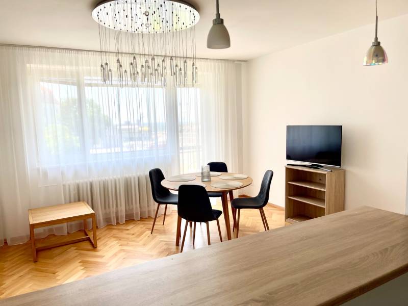 2-bedroom apartment with wooden flooring, dining table, TV, and modern lighting.