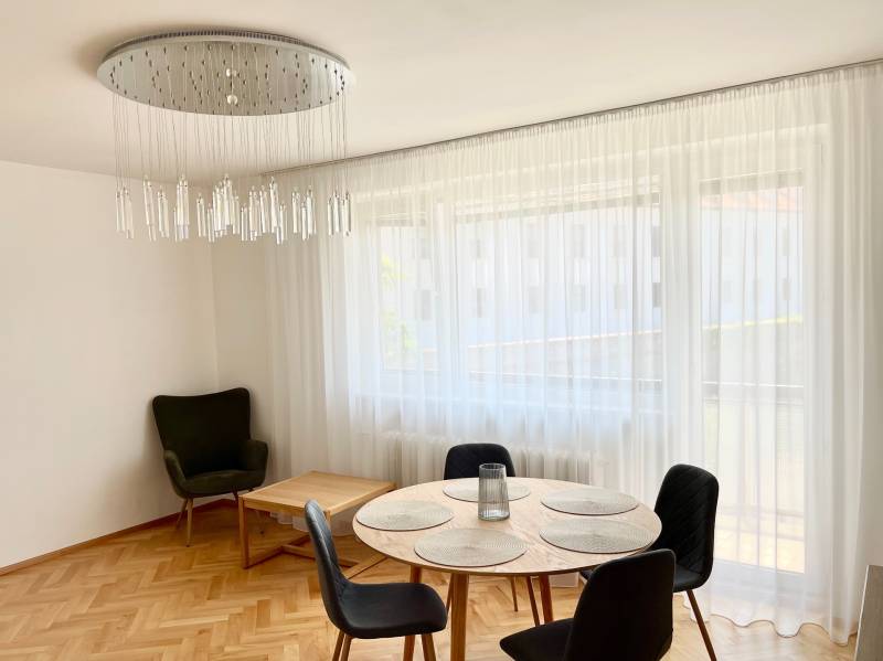 Dining area with a round table and curtains in a 2-room apartment, with an elegant chandelier.