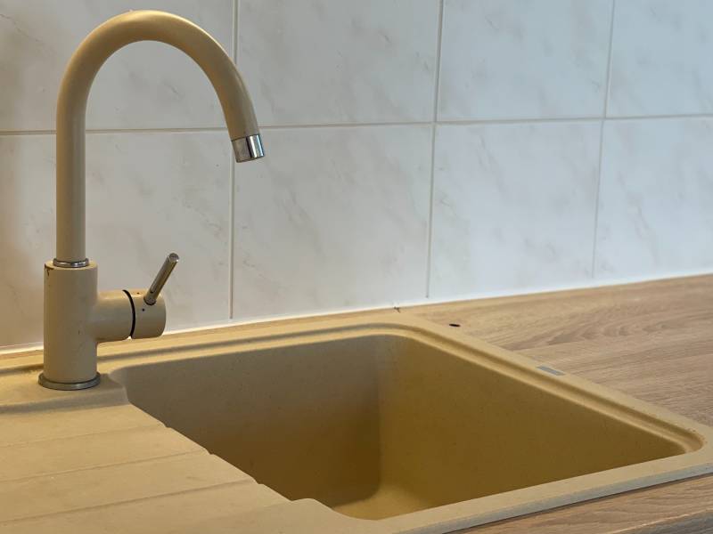 Kitchen sink and faucet in a 2-room apartment with a wooden countertop.