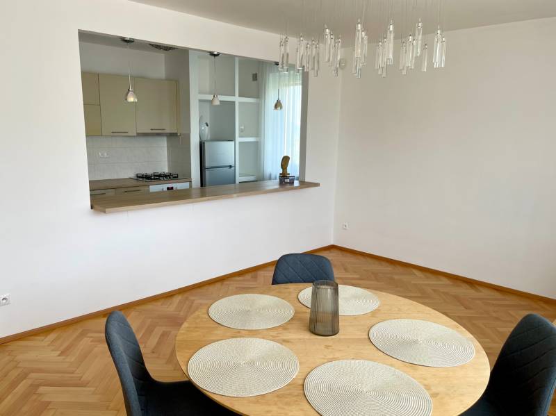 Dining table with four chairs, kitchen with a counter window in a 2-room apartment.
