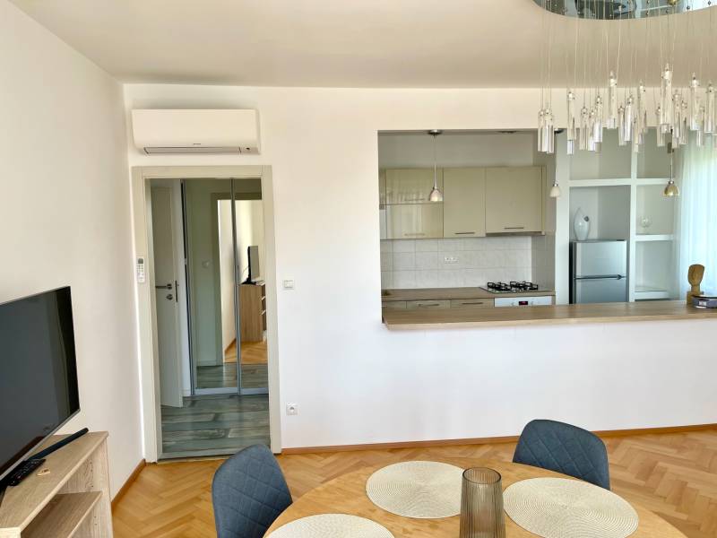 Living room with kitchen, air conditioning, mirrored wardrobe, parquet flooring in a 2-room apartment.