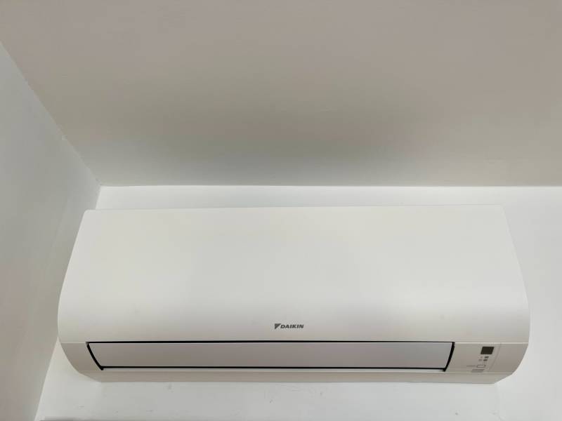 White Daikin air conditioner installed on a white wall in a 2-room apartment.