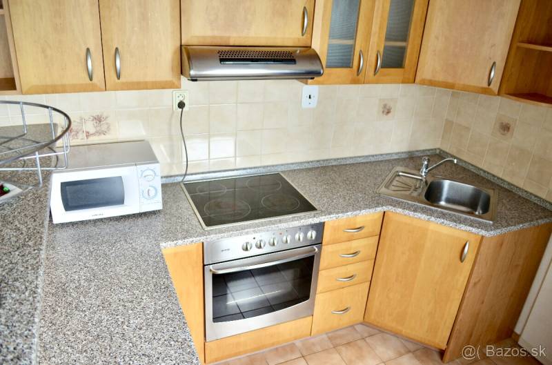 A kitchen unit in a studio apartment with a microwave, a cooktop, and a sink.