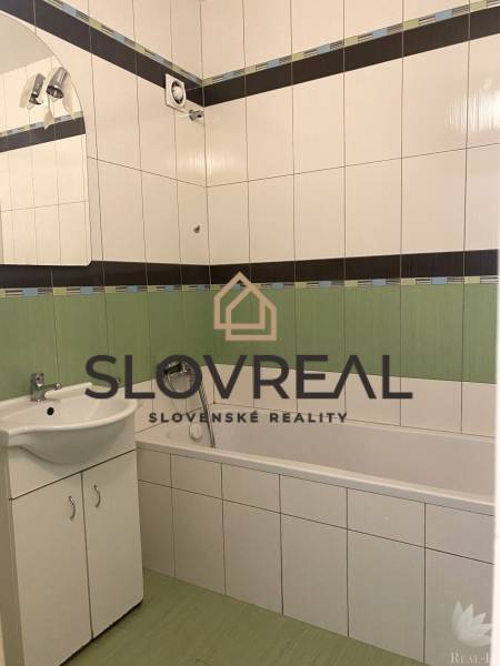 Bathroom in a 3-room apartment with a bathtub, sink, and tiles in white and green colors.