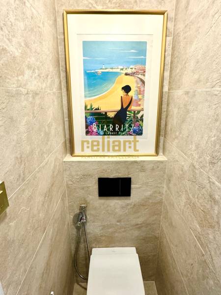 A bathroom in a 3-room apartment, with a picture above the toilet and tiles.