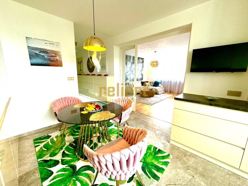Dining area with a round table, chairs, and a television in a 3-room apartment.