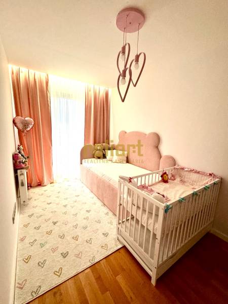 Children's room in a 3-room apartment with pink details and wooden flooring.