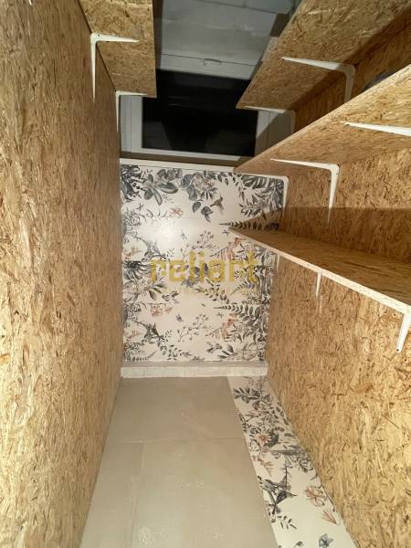 Storage space in a 3-room apartment with wooden shelves and floral wallpaper.