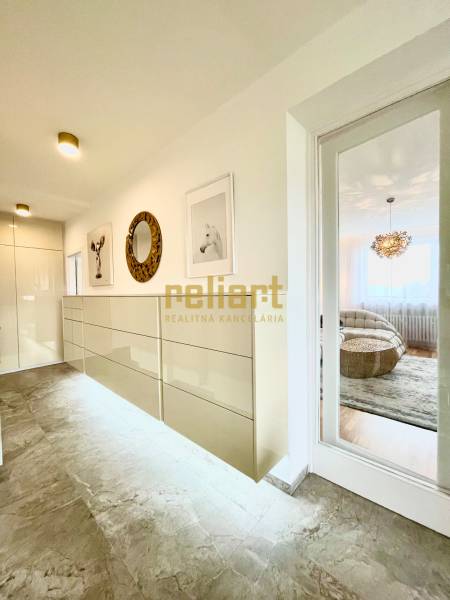 A hallway in a 3-room apartment with a tiled floor, decorative paintings, and a mirror.