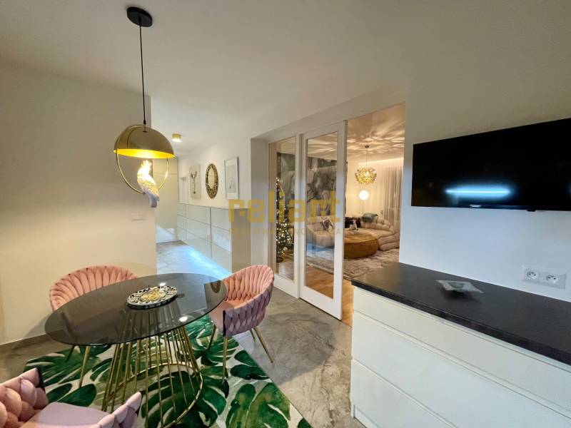Dining area with a round table, pink chairs, and interesting lighting in a 3-room apartment.