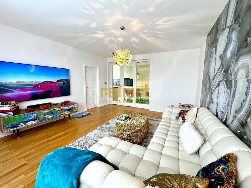 Living room in a three-room apartment with a stylish sofa and a television on the wall.