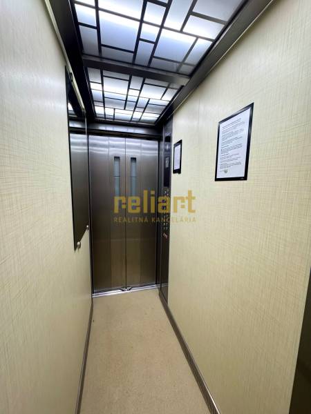 An elevator with an illuminated ceiling and stainless steel doors.