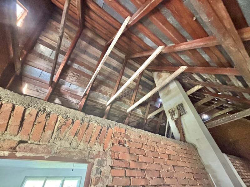 Attic in a family house with exposed roof structure and brick wall.