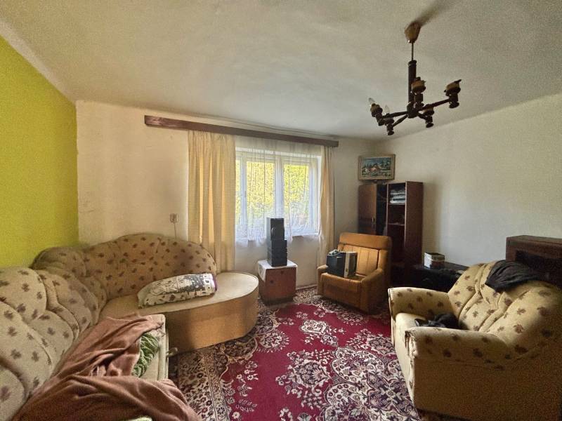 Living room in a family house with older furniture, carpet, chandeliers, and decorative elements.