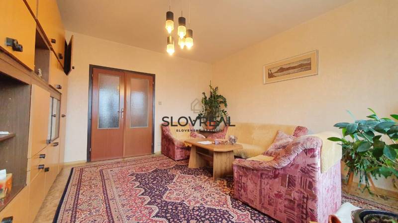 Living room in a 3-room apartment with a sofa, table, and carpet.