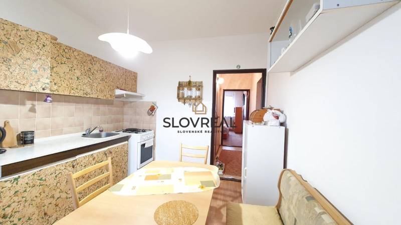 A kitchen in a 3-room apartment with a dining table and a gas stove.