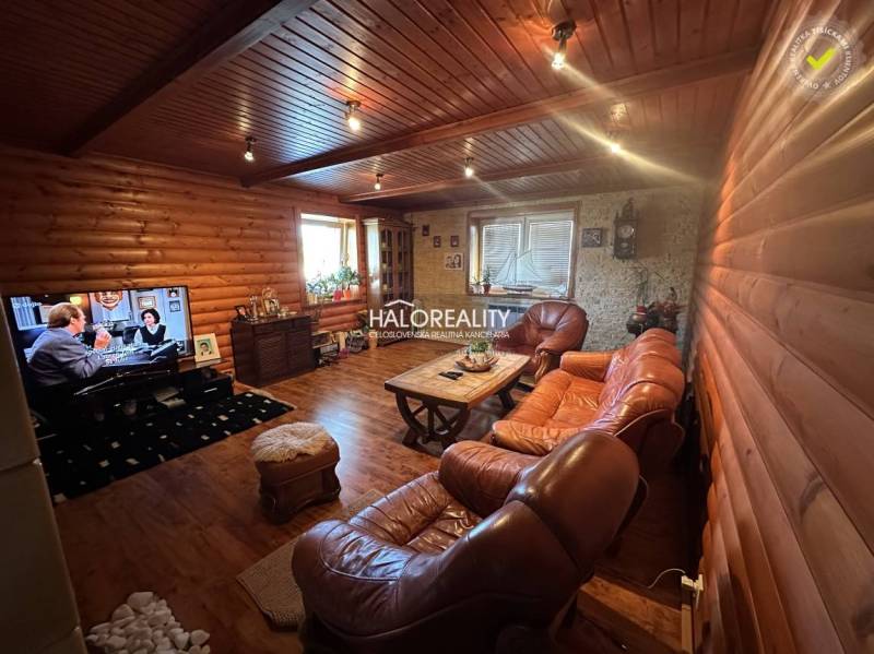 Living room in a family house with wooden paneling, leather seating, and a television.
