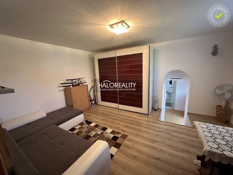 Bedroom with wooden floor, bed, and a view into the bathroom in a family house.