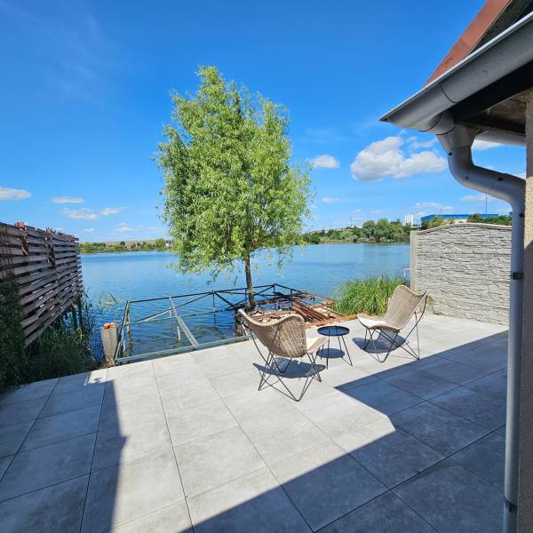 Terrace by the lake in Čaňa near the cottage with two chairs and a table.