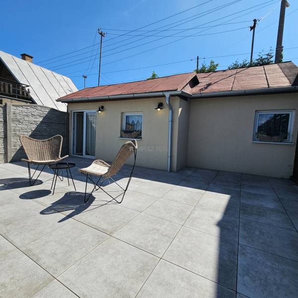 A cottage in Čaňa with a terrace, two chairs, and a table under the blue sky.