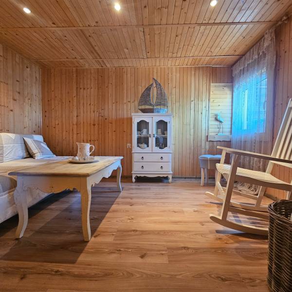 Interior of a cabin with a wooden floor, a swing, a table, and a display cabinet.
