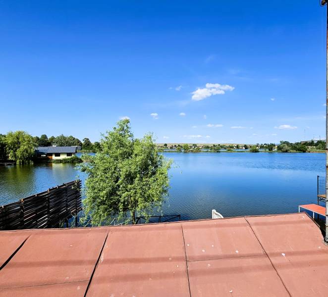 The view from the cottage in Čaňa to the lake with a blue sky and greenery.