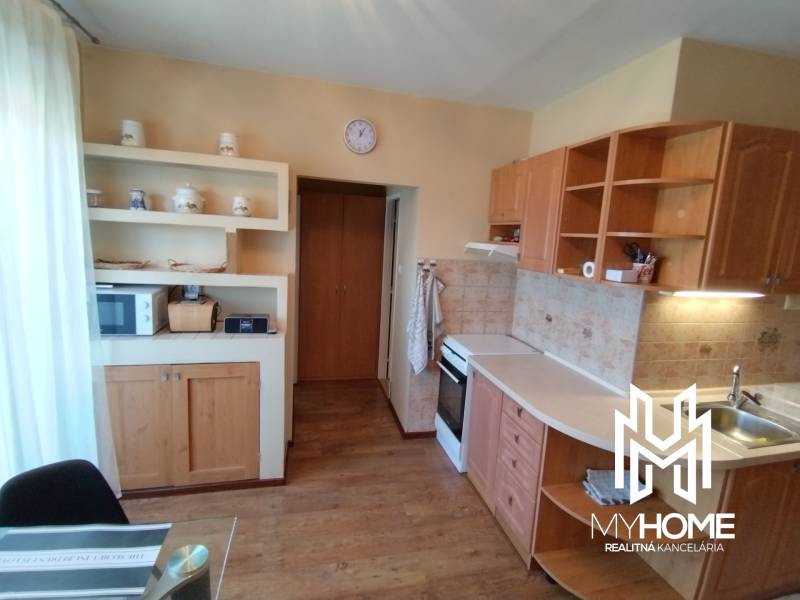 A kitchen in a 3-room apartment with wooden cabinets, appliances, and decorative shelves.