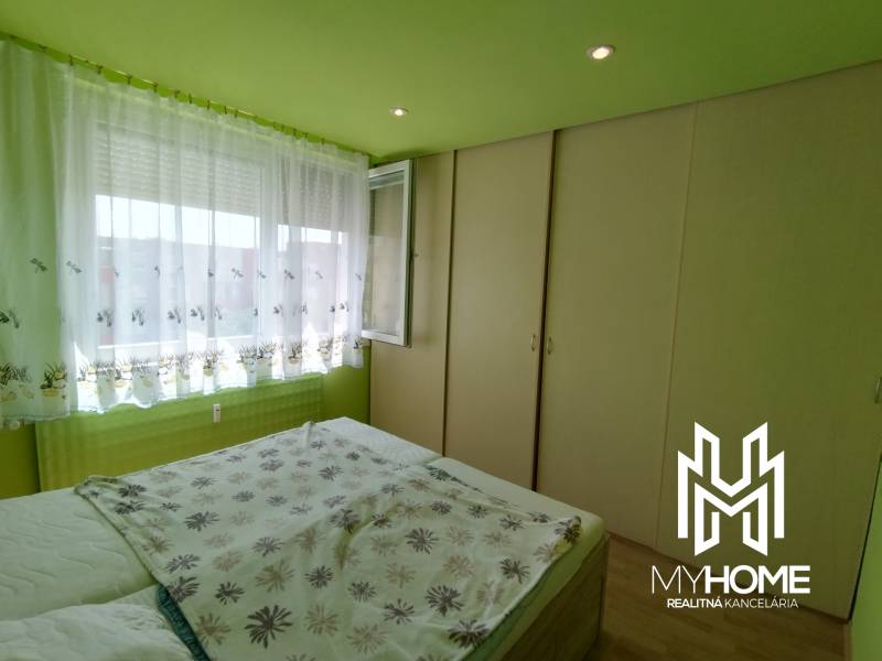 Bedroom in a 3-room apartment with built-in wardrobes and a large window with white curtains.