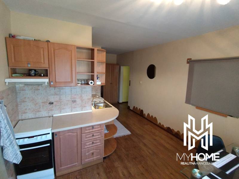 A kitchen with a wooden cabinet and a stove in a 3-room apartment.