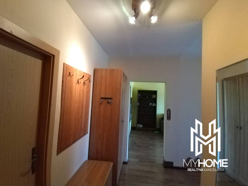 A hallway in a 3-room apartment with wooden furniture and hanging hooks for coats.