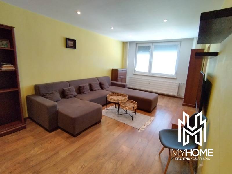 Living room in a 3-room apartment with a large brown sofa and wooden floors.