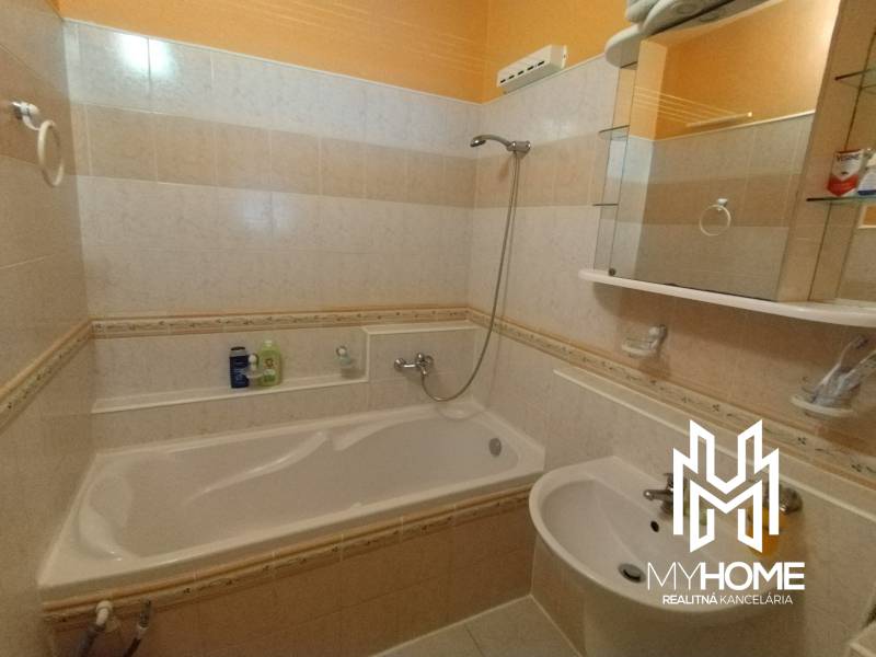 Bathroom with a bathtub and a sink in a 3-room apartment, tiles in shades of beige.
