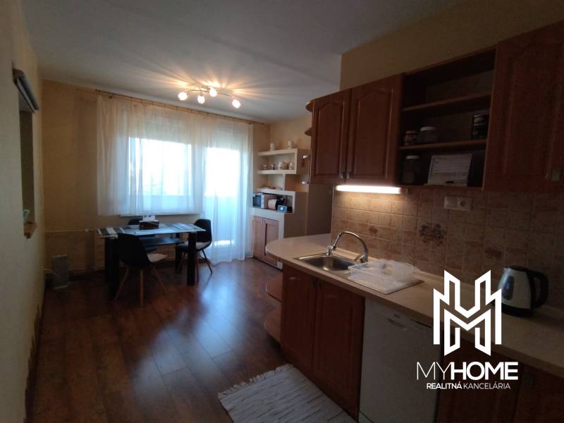 A kitchen in a 3-room apartment with a dining table and a wooden kitchen unit.