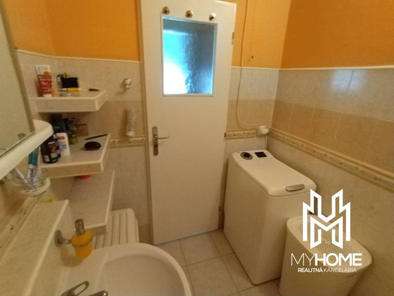 A bathroom in a 3-room apartment with a sink, washing machine, and shelves for cosmetics.