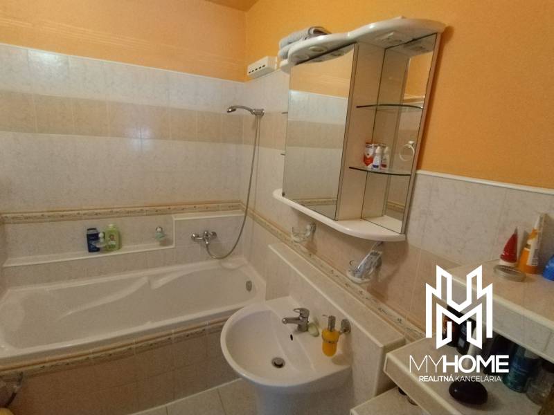A bathroom in a 3-room apartment with a bathtub, a sink, and a mirrored cabinet.