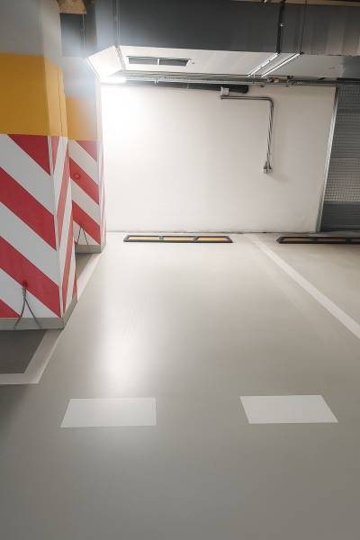 A parking space in garages with warning stripes on the walls and ventilation.
