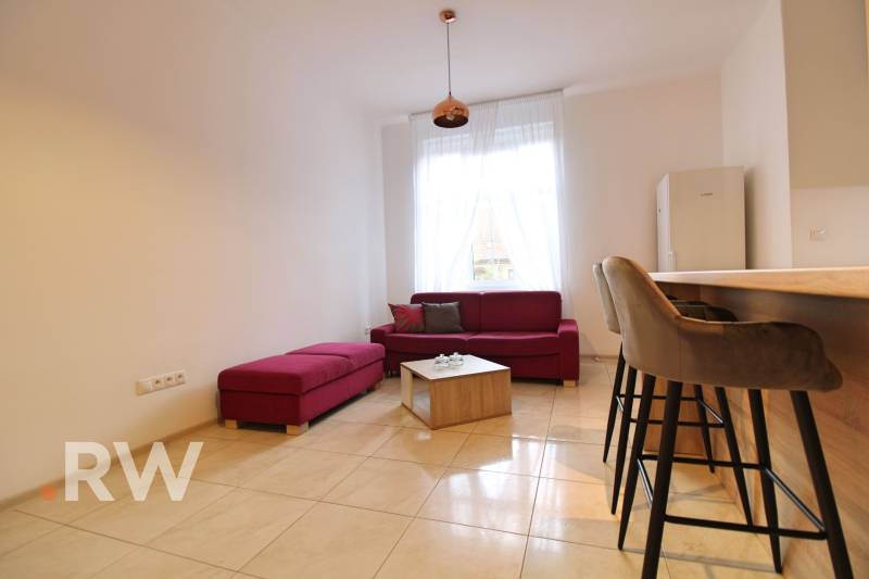 Living room with a red sofa and bar stools in a 3-room apartment.