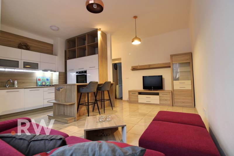 Living room with kitchen and dining area in a 3-room apartment with a purple sofa.