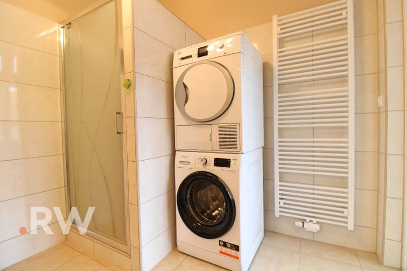 Bathroom with a washing machine, dryer, shower corner, and ladder radiator in a 3-room apartment.