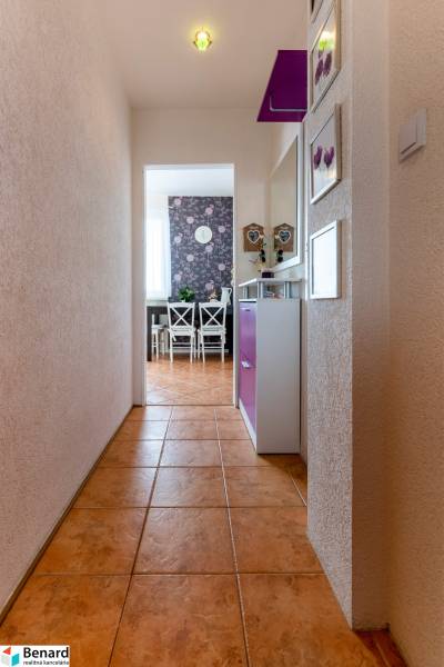 A hallway with a ceramic floor leading to the dining room in a 3-room apartment, with decorative wallpaper.