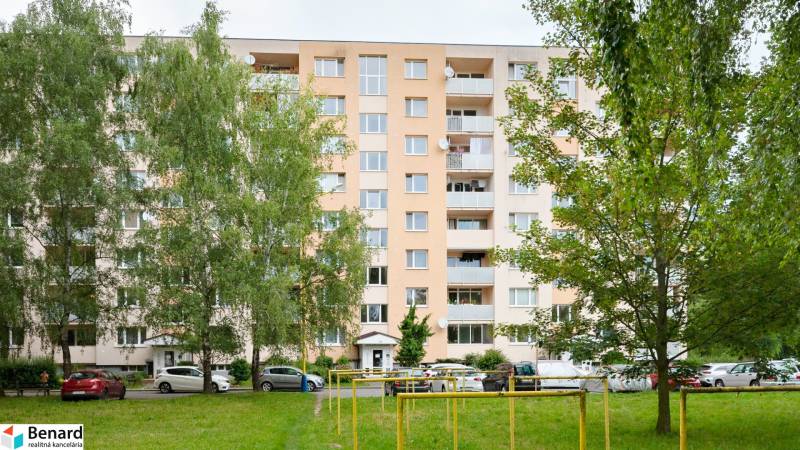 An apartment building on Prostějovská Street in Prešov surrounded by greenery with a parking lot.