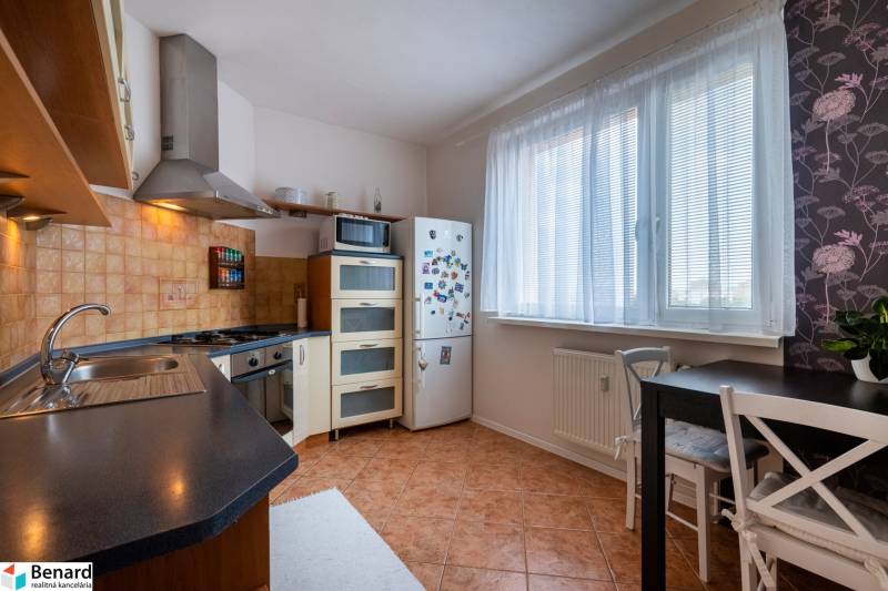 A kitchen in a 3-room apartment with a combination stove, refrigerator, and dining table.