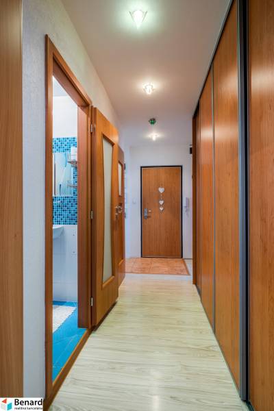 A hallway in a 3-room apartment with wooden doors and built-in wardrobes.