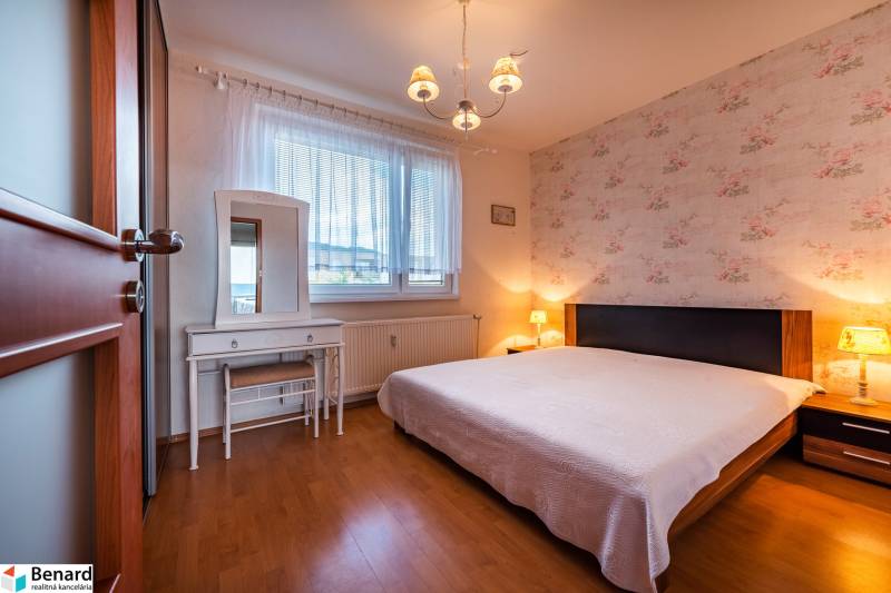 Bedroom in a 3-room apartment with a bed, dressing table, and floral wallpaper.