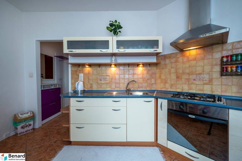 A kitchen in a 3-room apartment with a cooktop, sink, and storage cabinets.